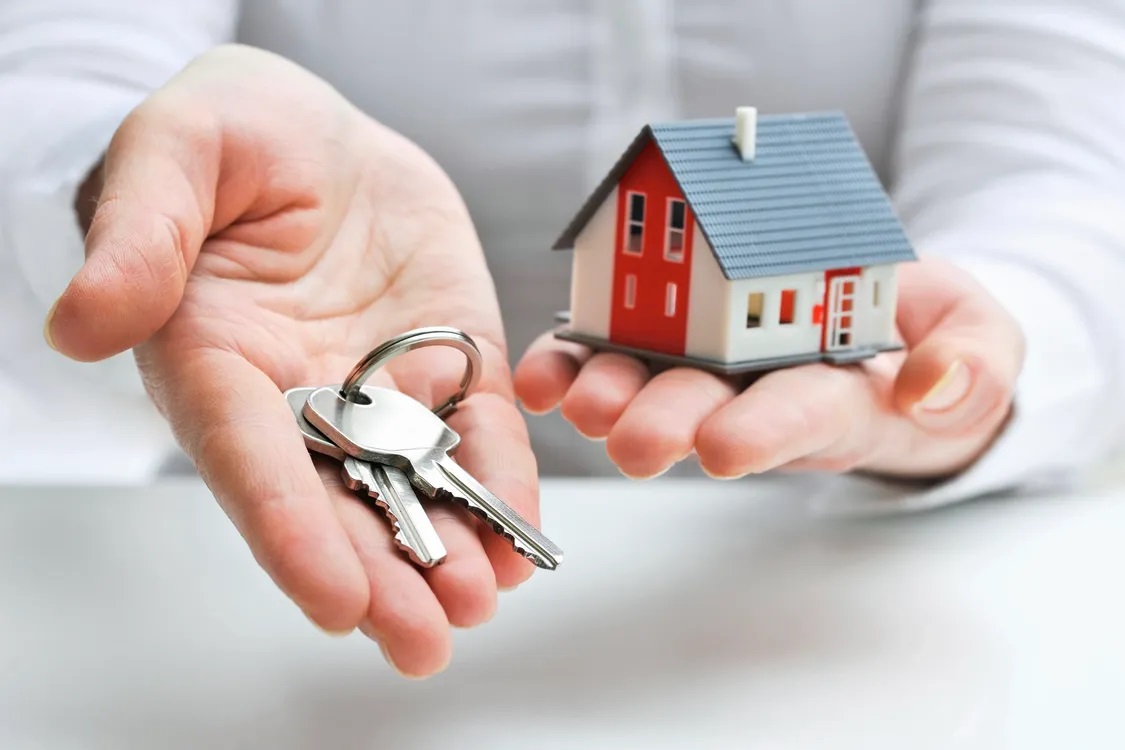 hand holding keys and a small home